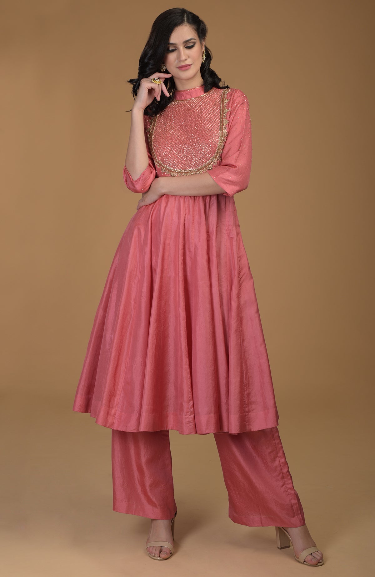 A woman models a peach echo kalidaar suit with zardozi hand embroidery.