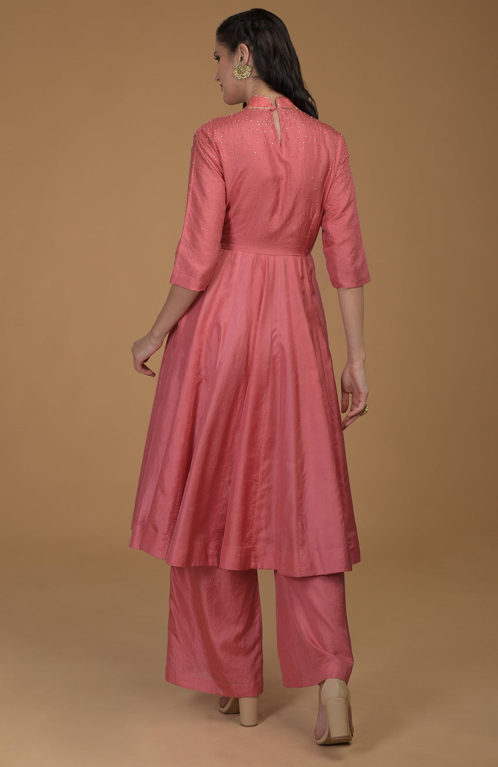 A woman models a peach echo kalidaar suit with zardozi hand embroidery.