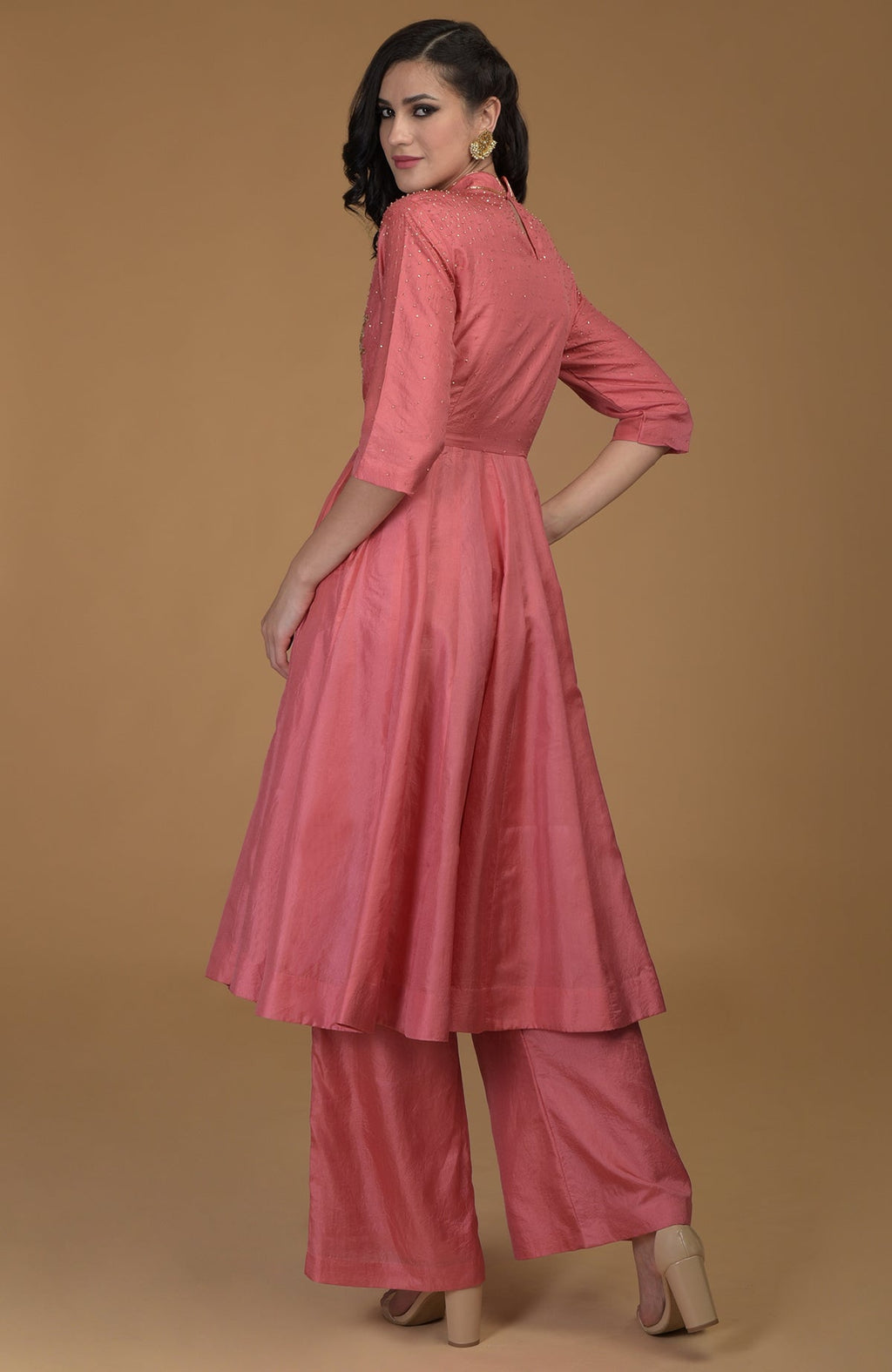 A woman models a peach echo kalidaar suit with zardozi hand embroidery.