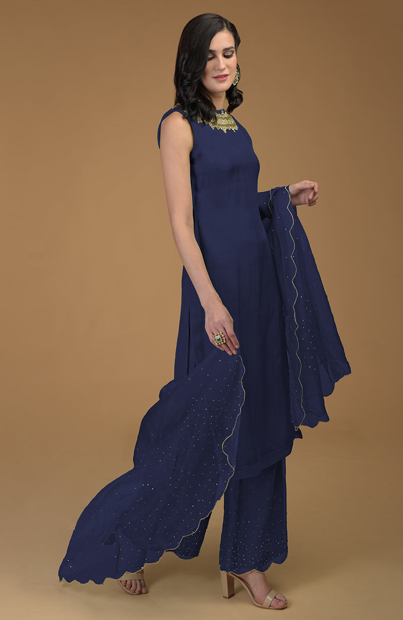 A woman models a navy blue kurta set with zardozi embroidery and scalloped hems.