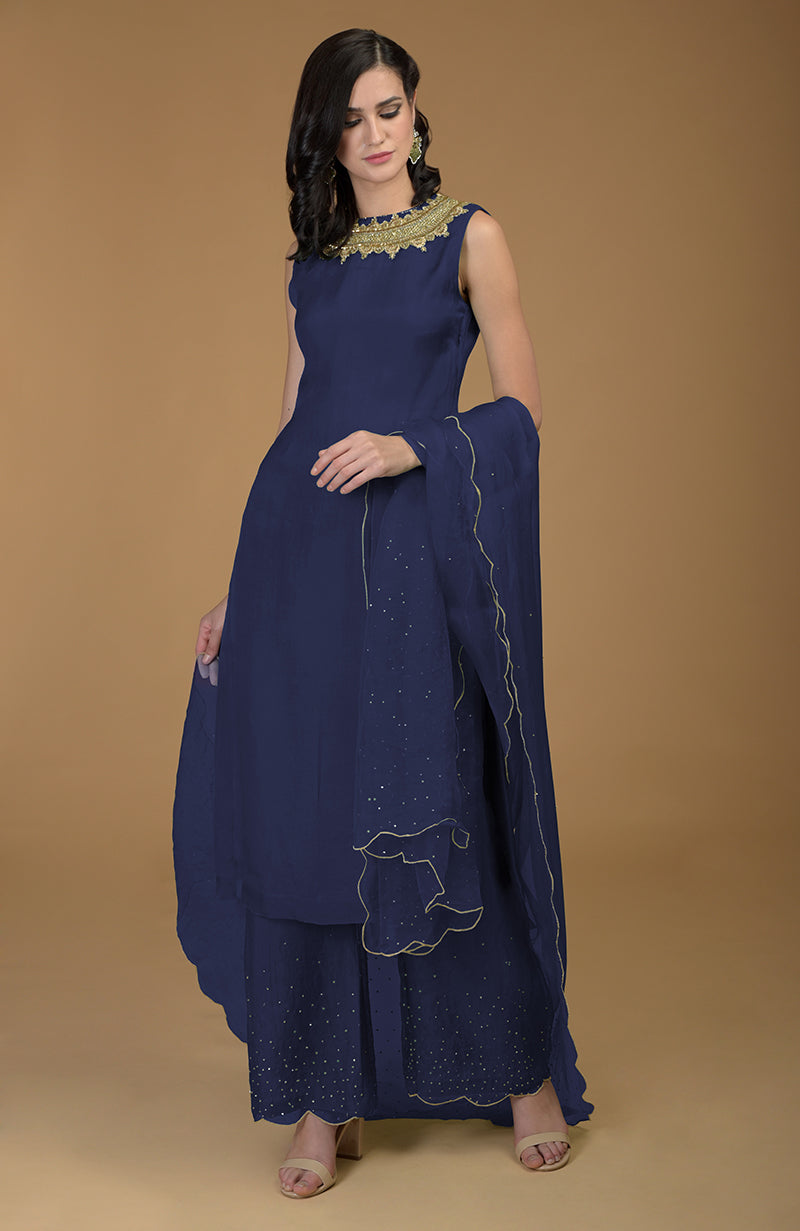 A woman models a navy blue kurta set with gold zardozi embroidery.
