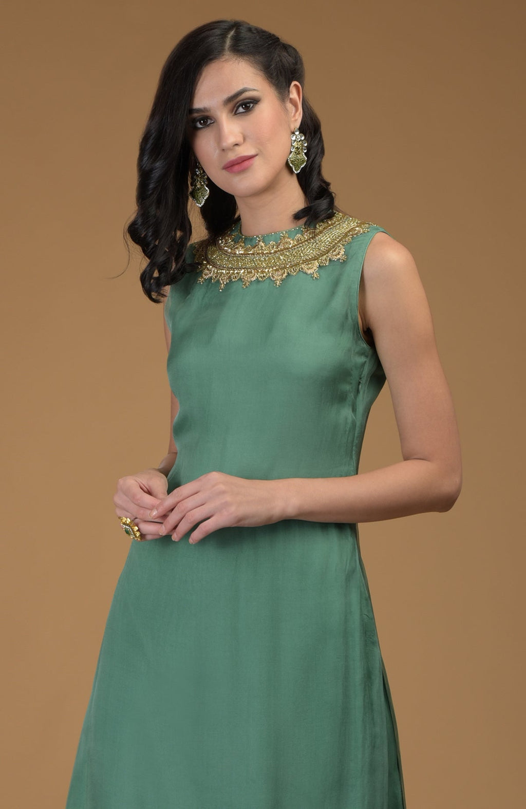 A woman models a green kurta with gold zardozi embroidery on the neckline.