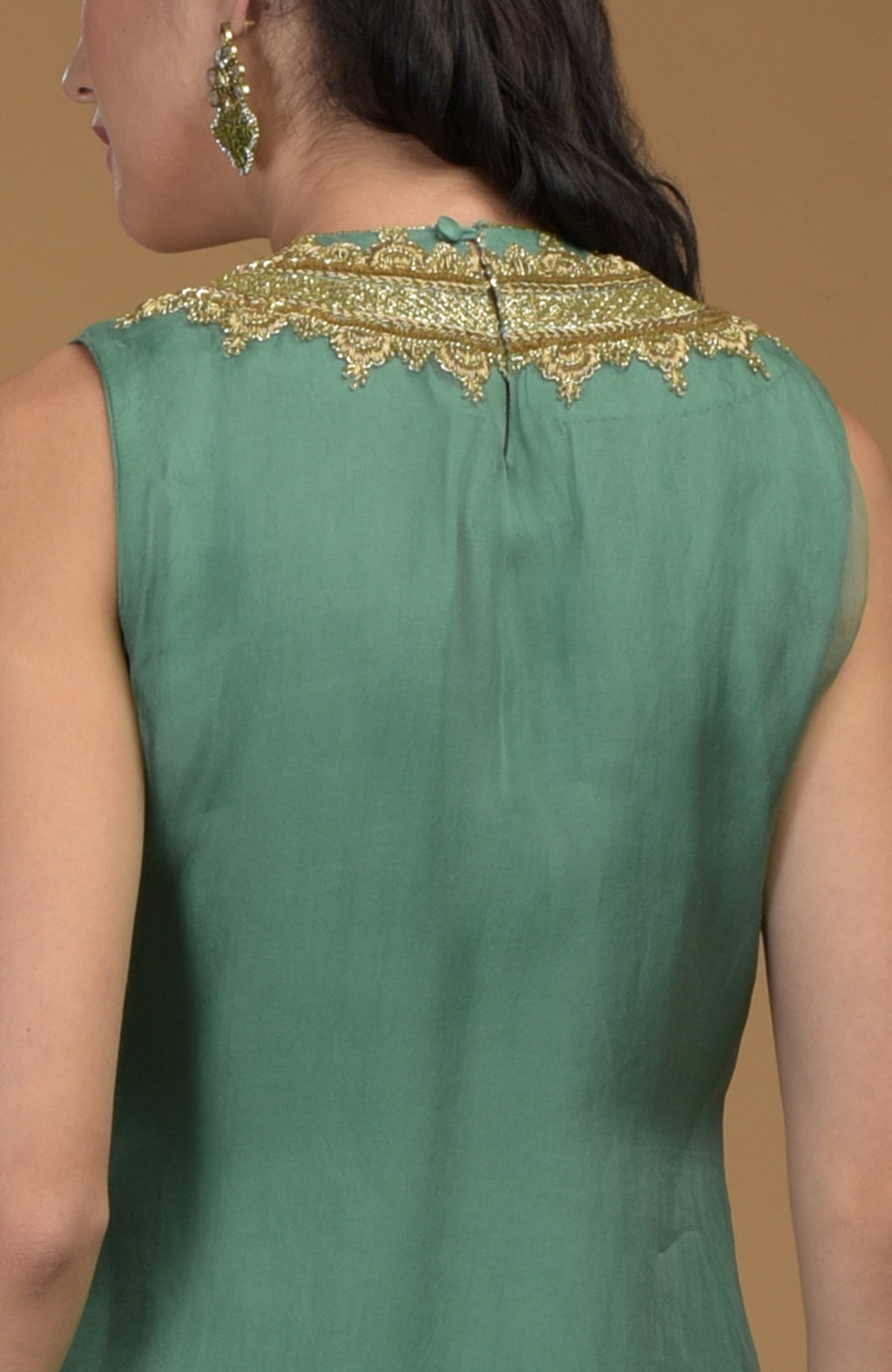 A woman models the back of a green kurta with gold zardozi embroidery on the neckline.