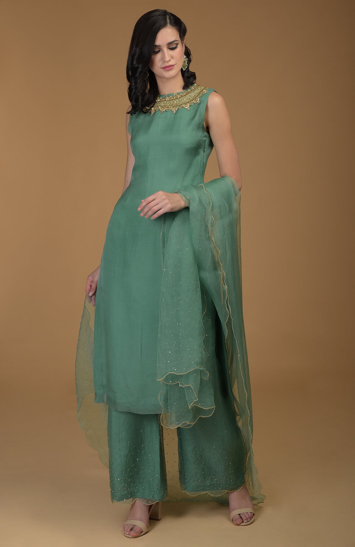 A woman models a green kurta set with gold zardozi embroidery and sheer dupatta.