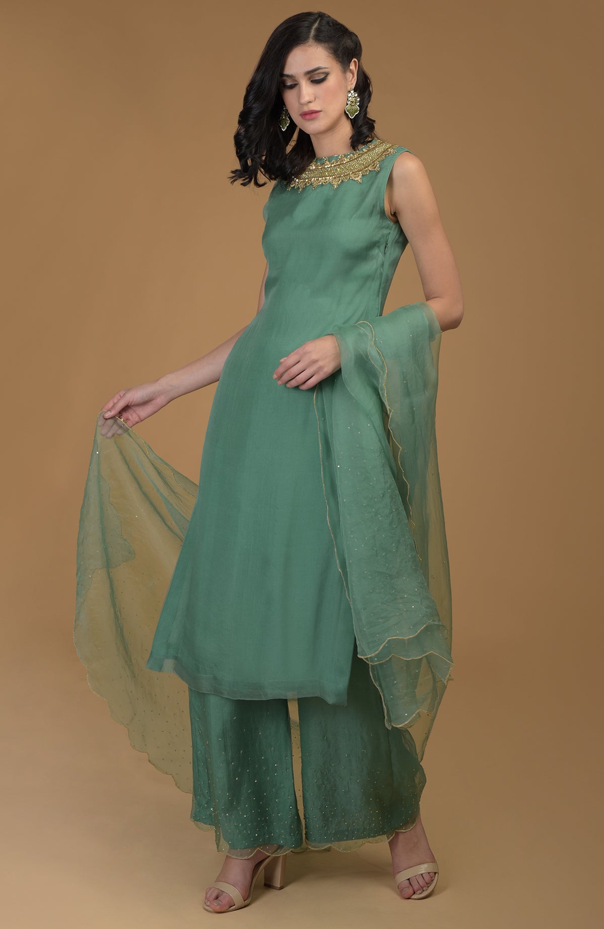 A woman models a green zardozi hand-embroidered kurta set with wide-leg pants and a dupatta.