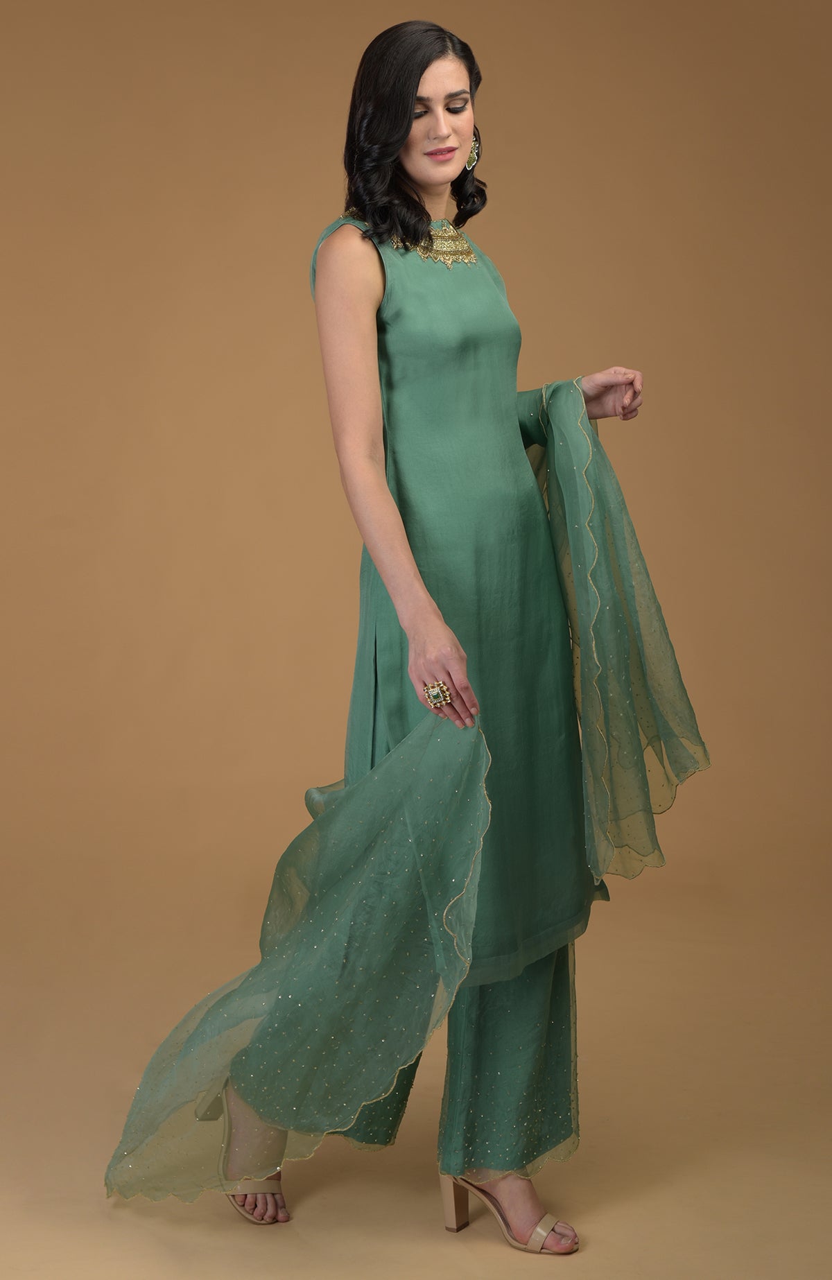 A woman models a green kurta set with zardozi embroidery and a sheer dupatta.