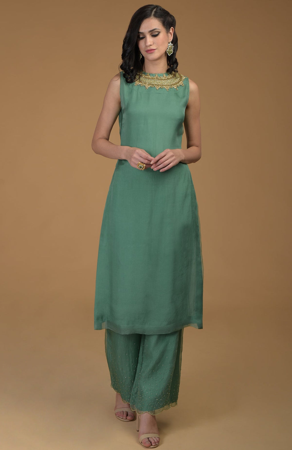 A woman models a green kurta set with gold zardozi embroidery.