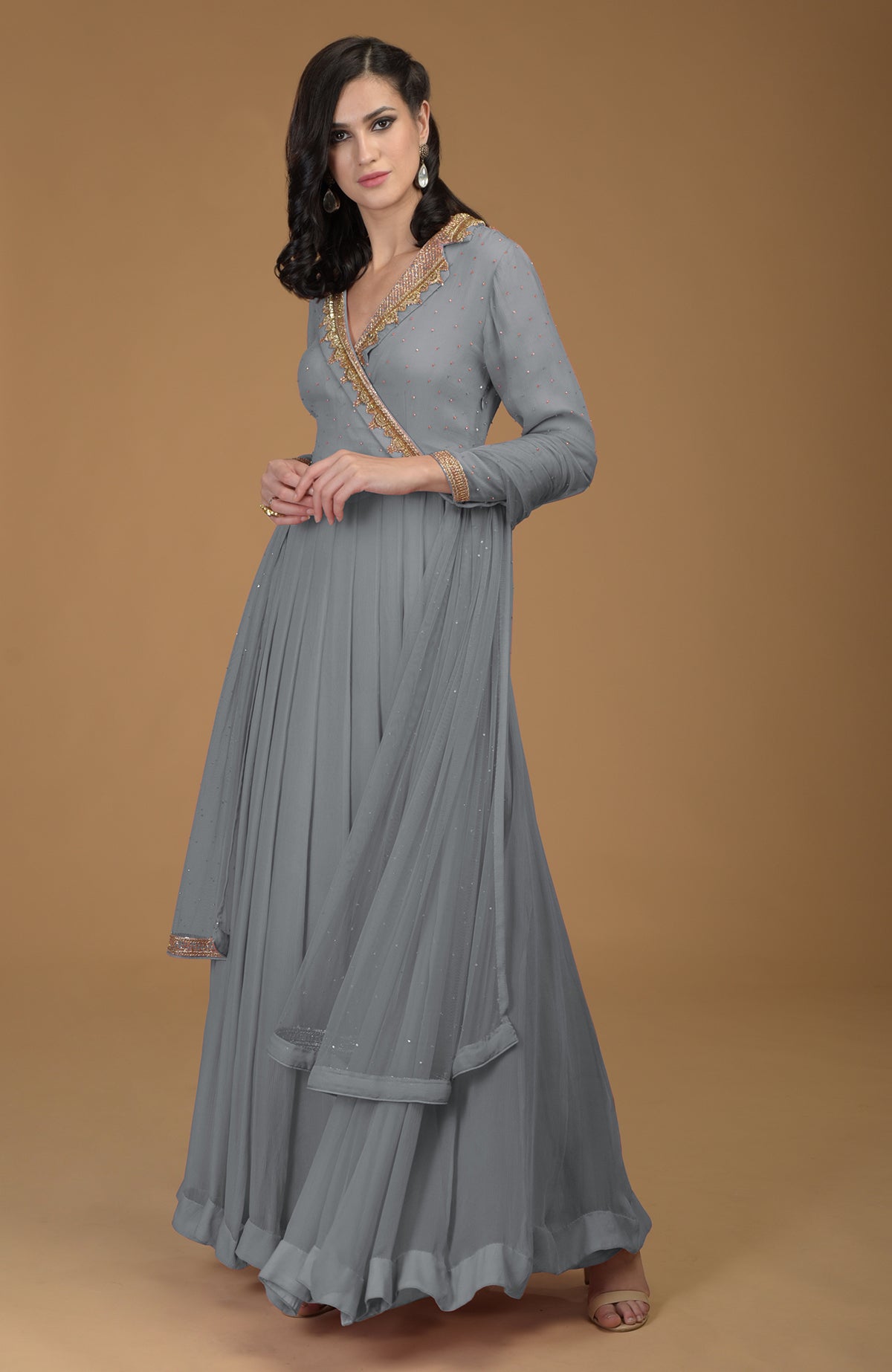 A woman models a gray kalidaar dress with gold zardozi embroidery and a net dupatta.