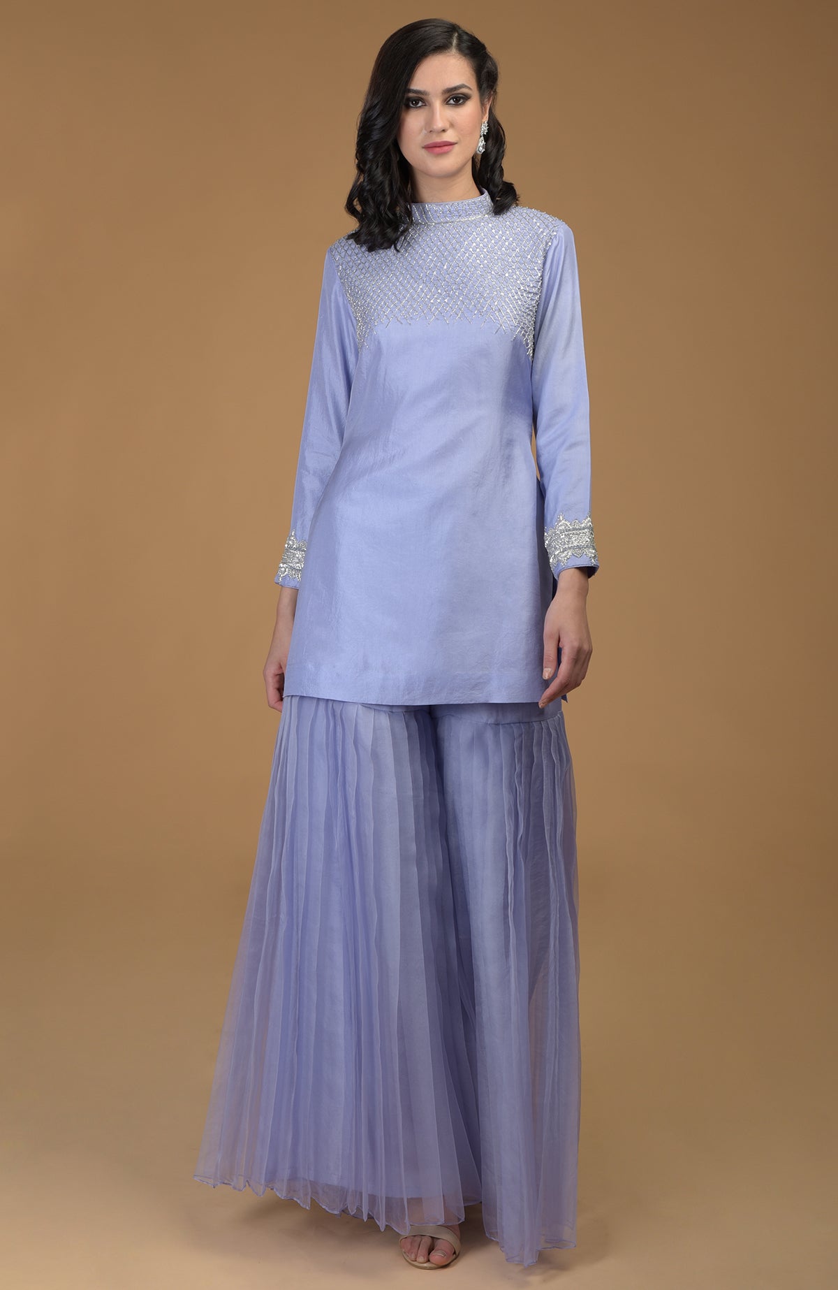 A woman models a pastel lilac kurta with zardozi embroidery and pleated gharara pants.