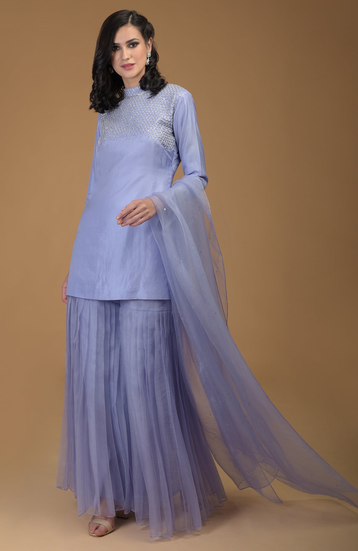 A woman models a pastel lilac gharara set with zardozi embroidery.