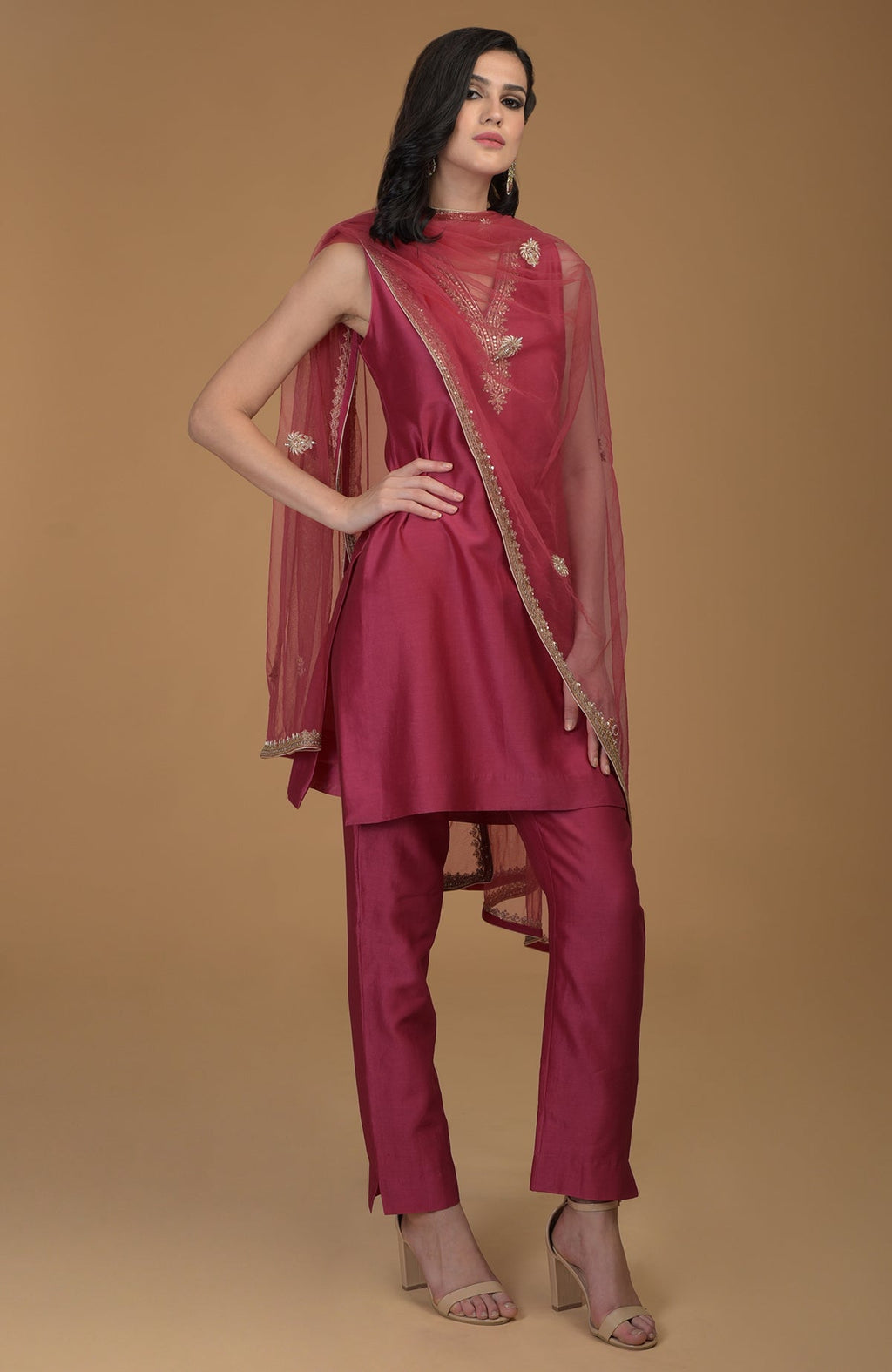 A woman models a ruby red zardozi hand-embroidered suit with a sheer dupatta.