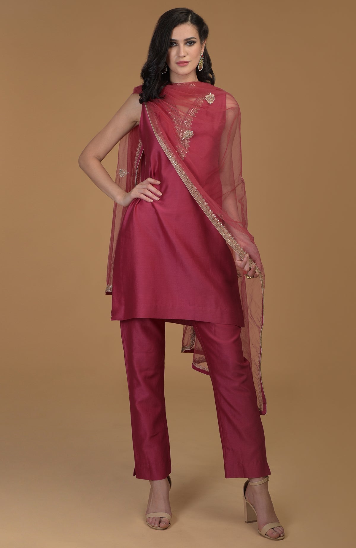 A woman models a ruby red zardozi hand-embroidered suit with a sheer dupatta.