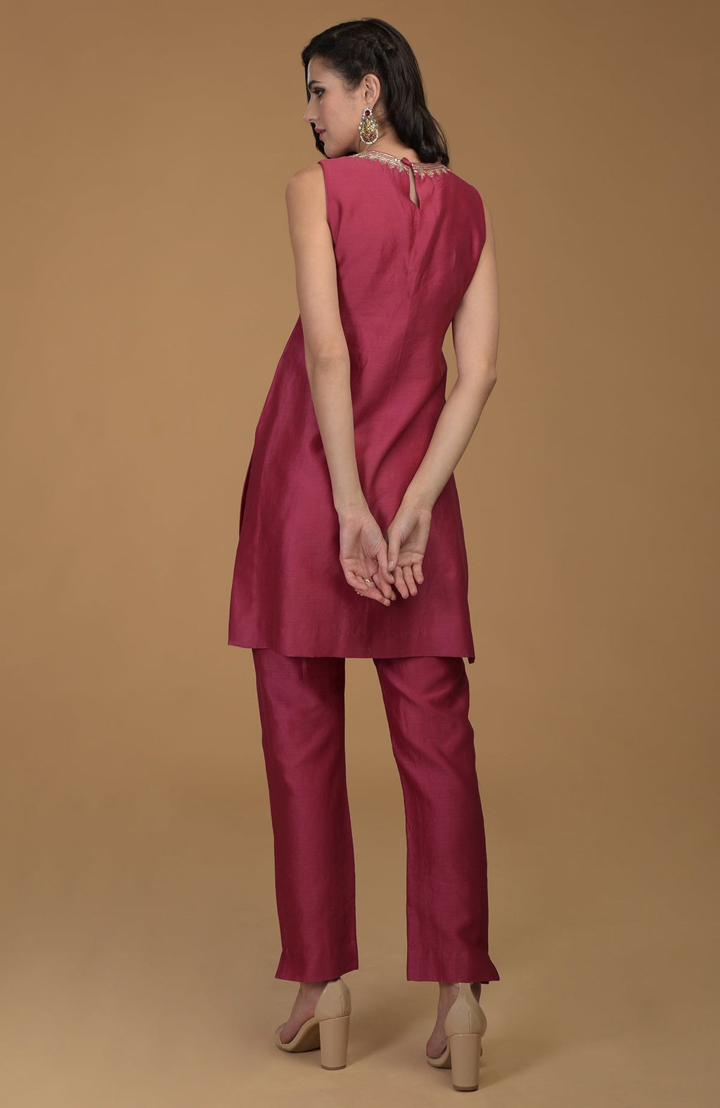 A woman models a ruby red two-piece suit with zardozi embroidery.