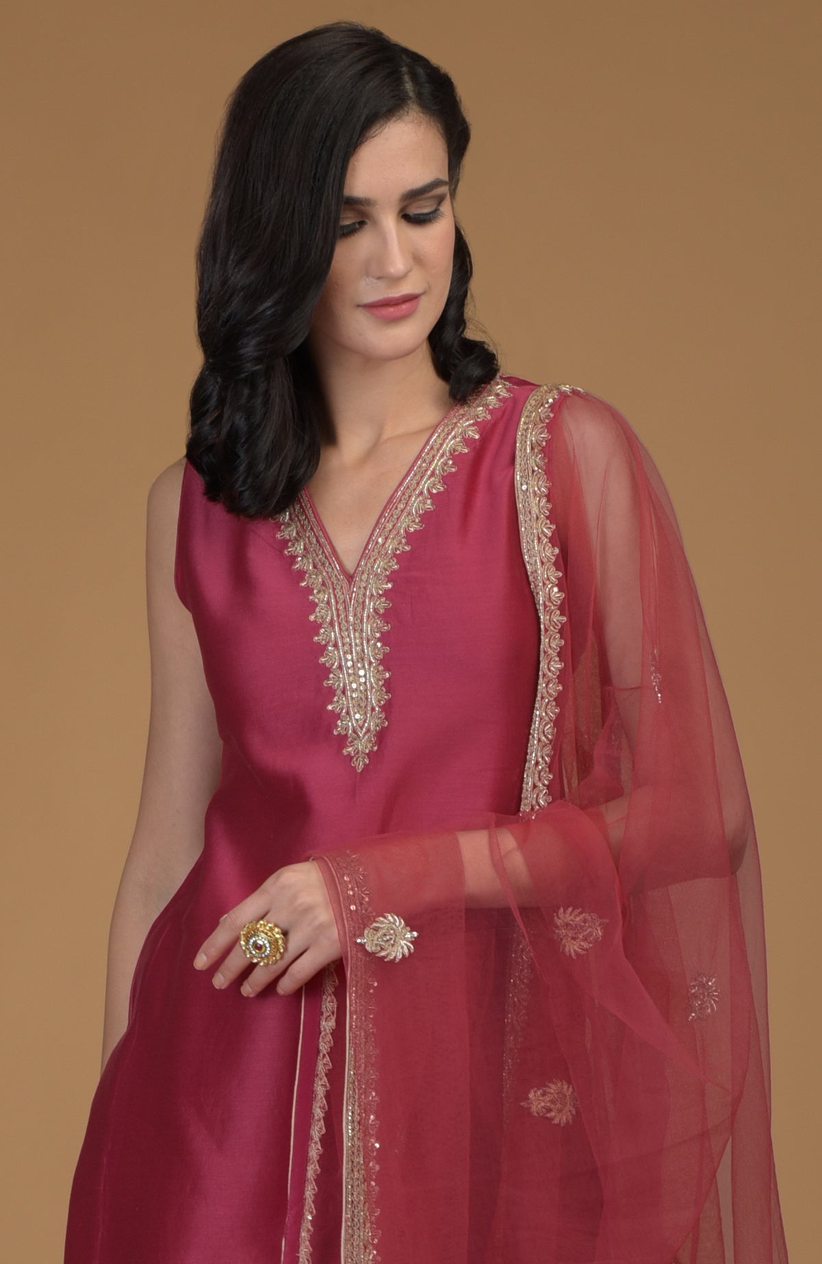 A woman models a ruby red zardozi hand-embroidered suit with a sheer dupatta.