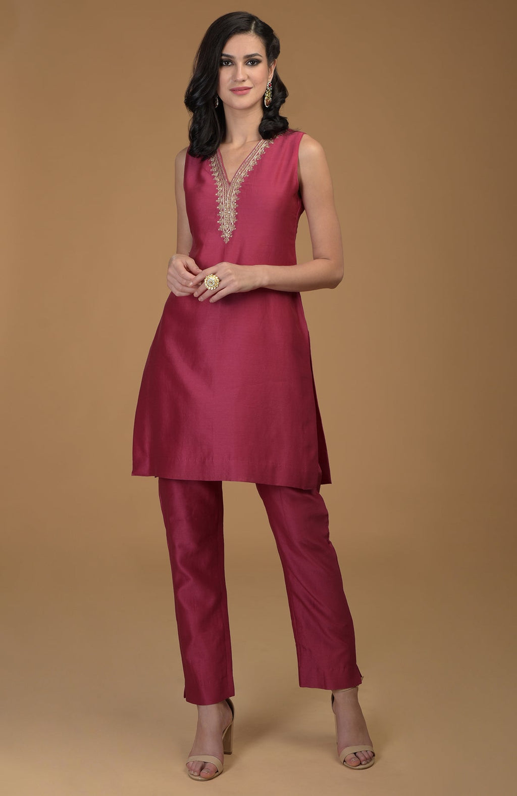 A woman models a ruby red two-piece suit with gold embroidered neckline.