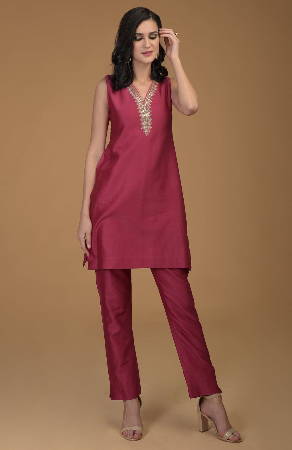 A woman models a ruby red two-piece suit with gold embroidered neckline.