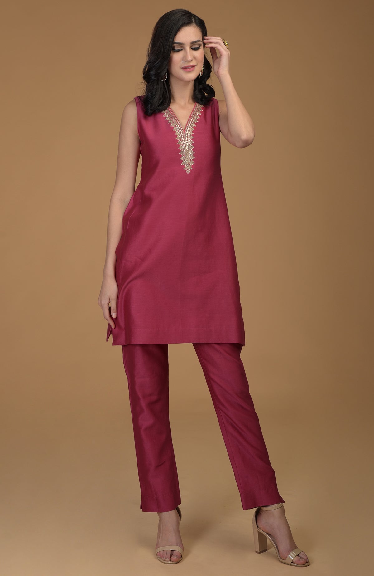 A woman models a ruby red two-piece suit with gold embroidered neckline.