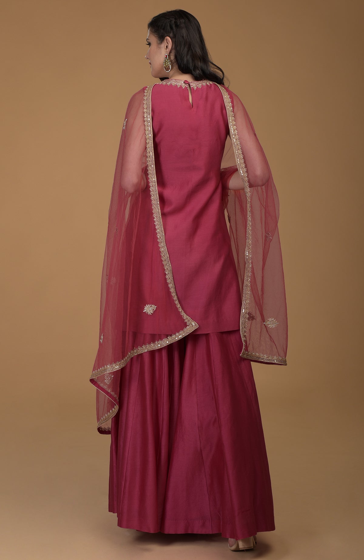 Ruby red gharara suit with gold zardozi embroidery on the dupatta and kurta neckline.