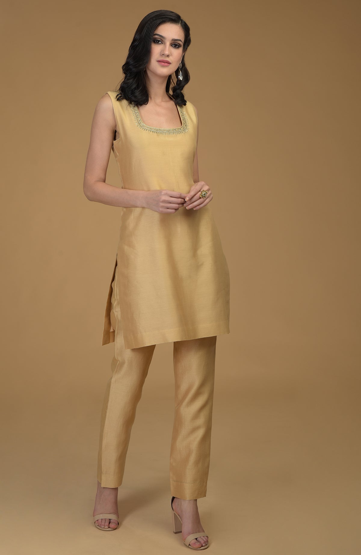 A woman models a nude gold two-piece suit with zardozi hand embroidery.