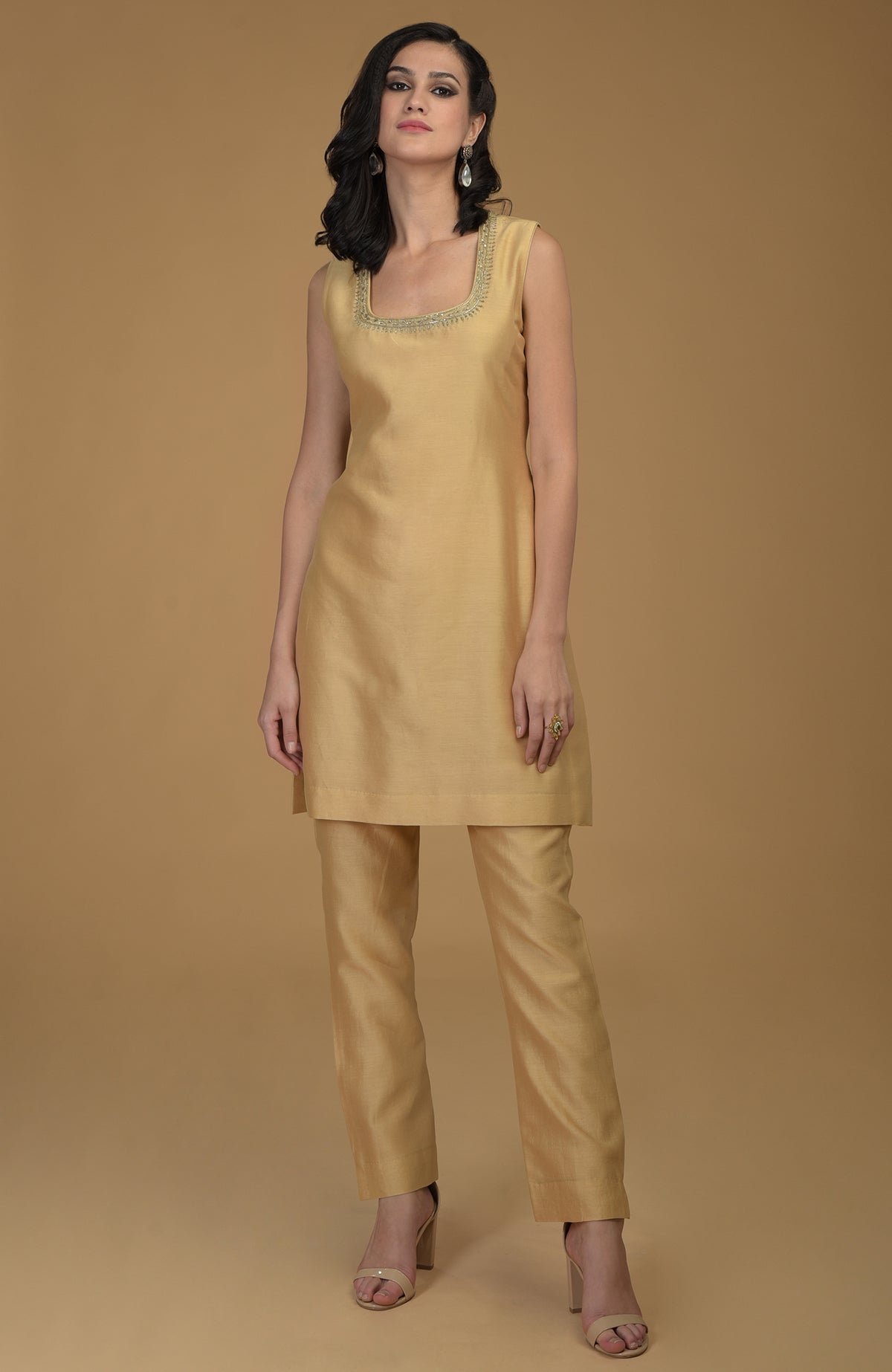 A woman models a nude gold two-piece suit with Zardozi hand embroidery.