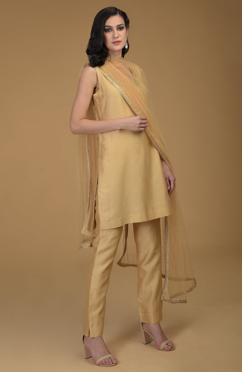 A woman models a nude gold zardozi hand-embroidered suit with a sheer dupatta.