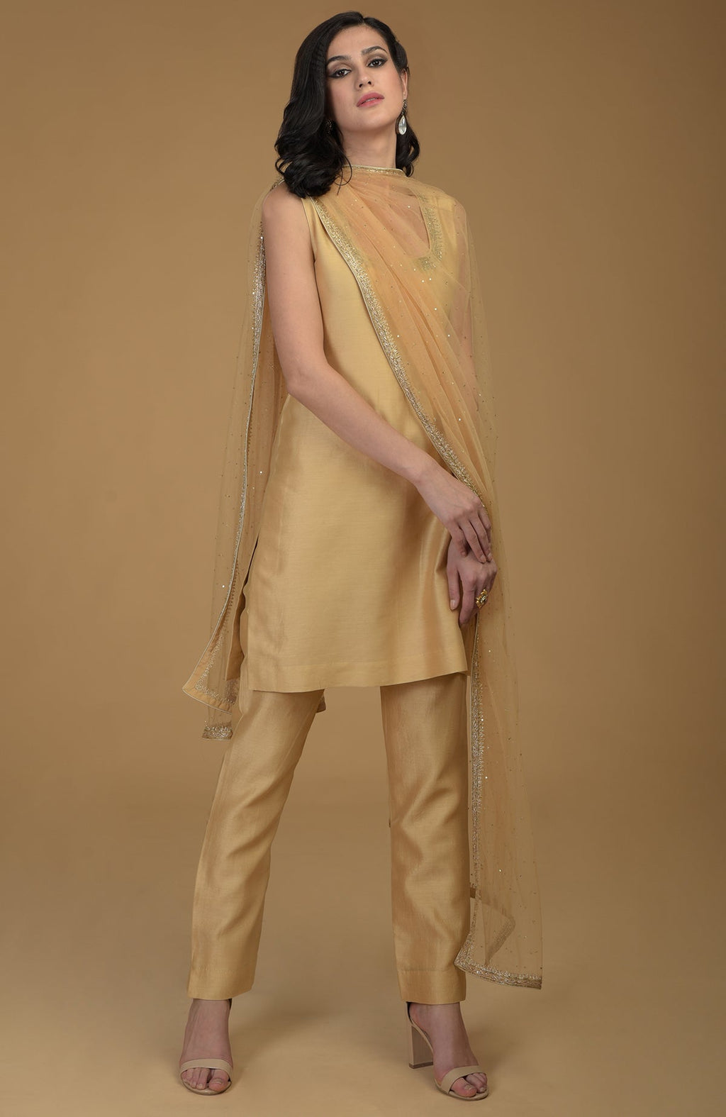 A woman models a nude gold zardozi hand-embroidered suit with a sheer dupatta.