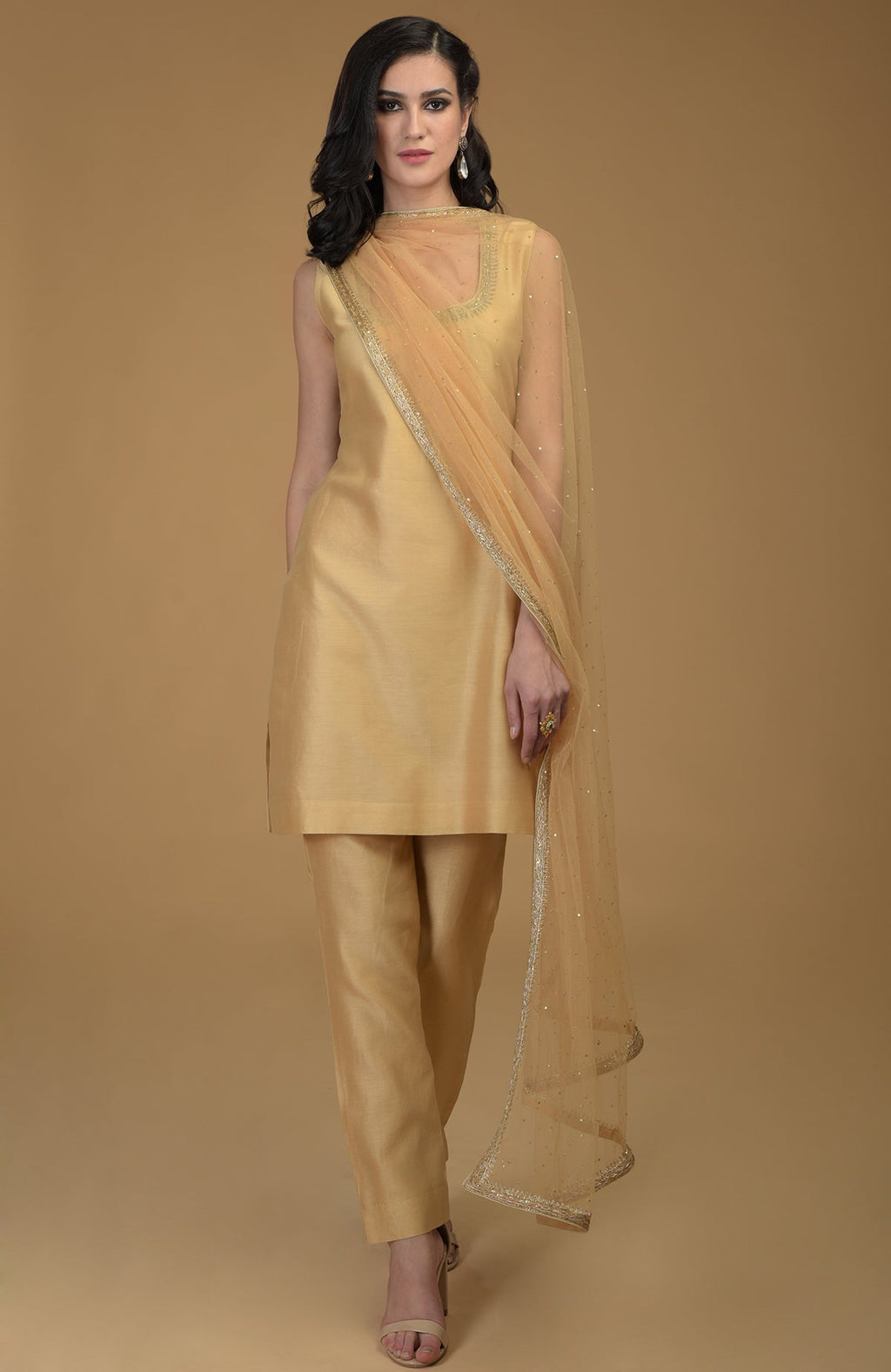 A woman models a nude gold zardozi hand-embroidered suit with a sheer dupatta.