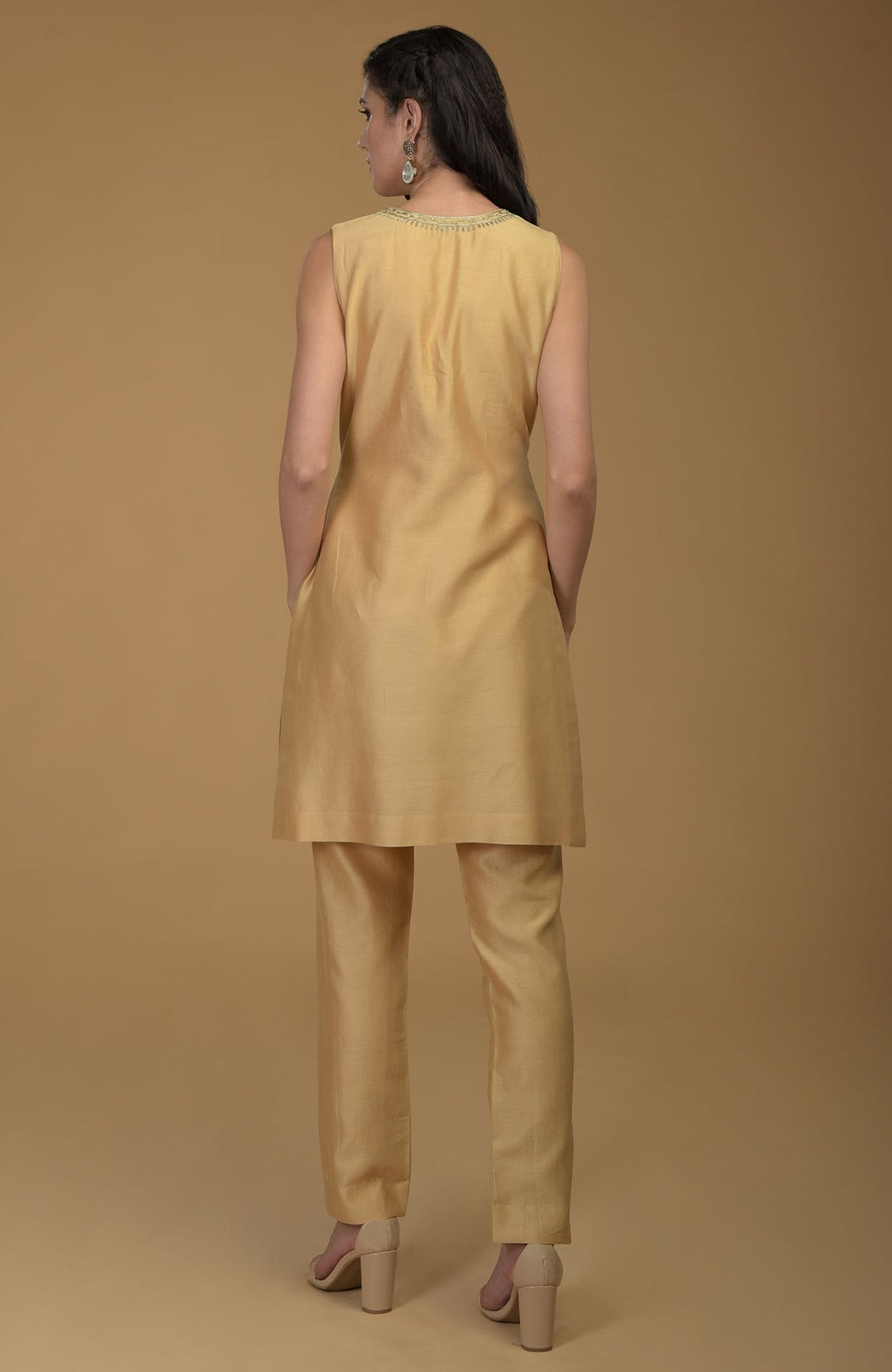 A woman models a nude gold two-piece suit with Zardozi hand embroidery.