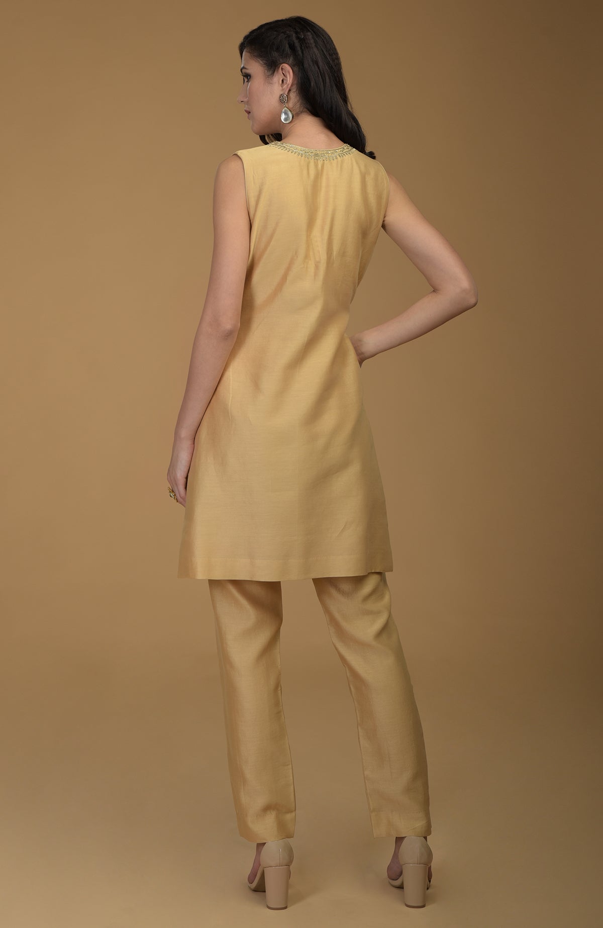 A woman models a nude gold two-piece suit with Zardozi hand embroidery.