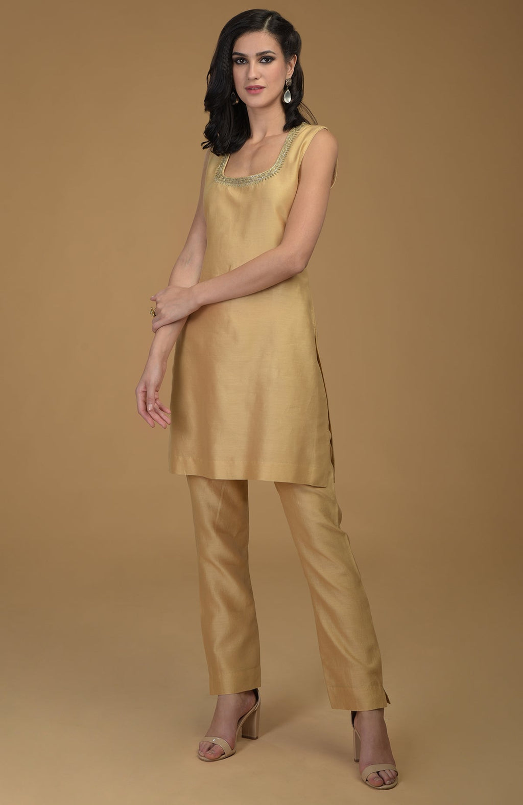 A woman models a nude gold two-piece suit with zardozi hand embroidery.