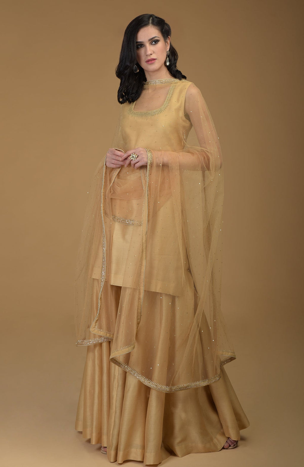 A woman models a nude gold zardozi hand embroidered gharara suit.