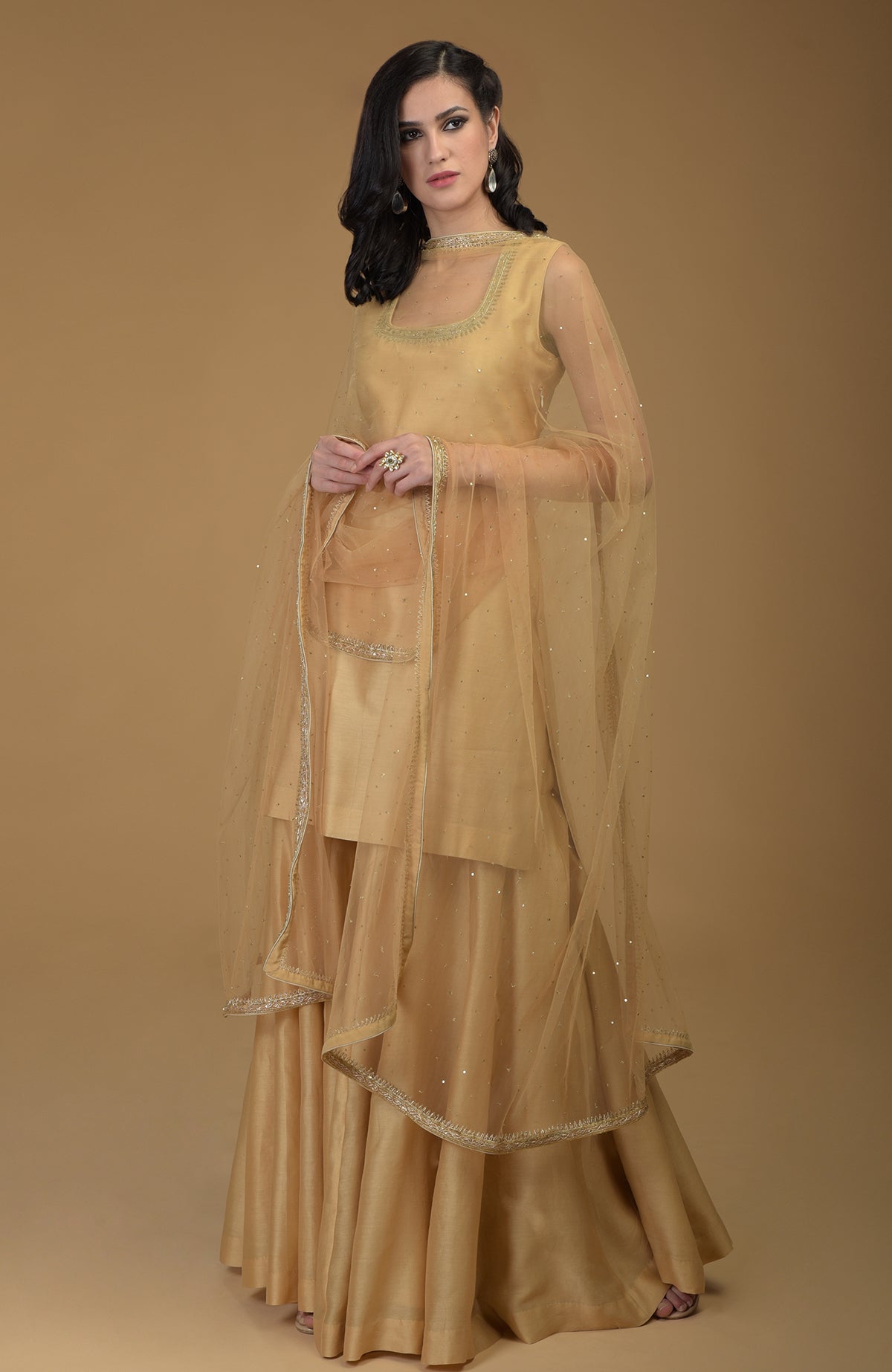 A woman models a nude gold zardozi hand embroidered gharara suit.