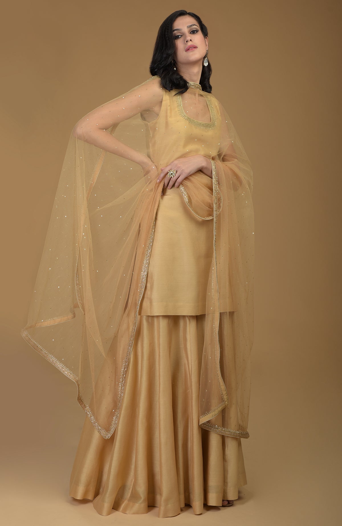 Nude gold zardozi hand embroidered gharara suit with a sheer dupatta.