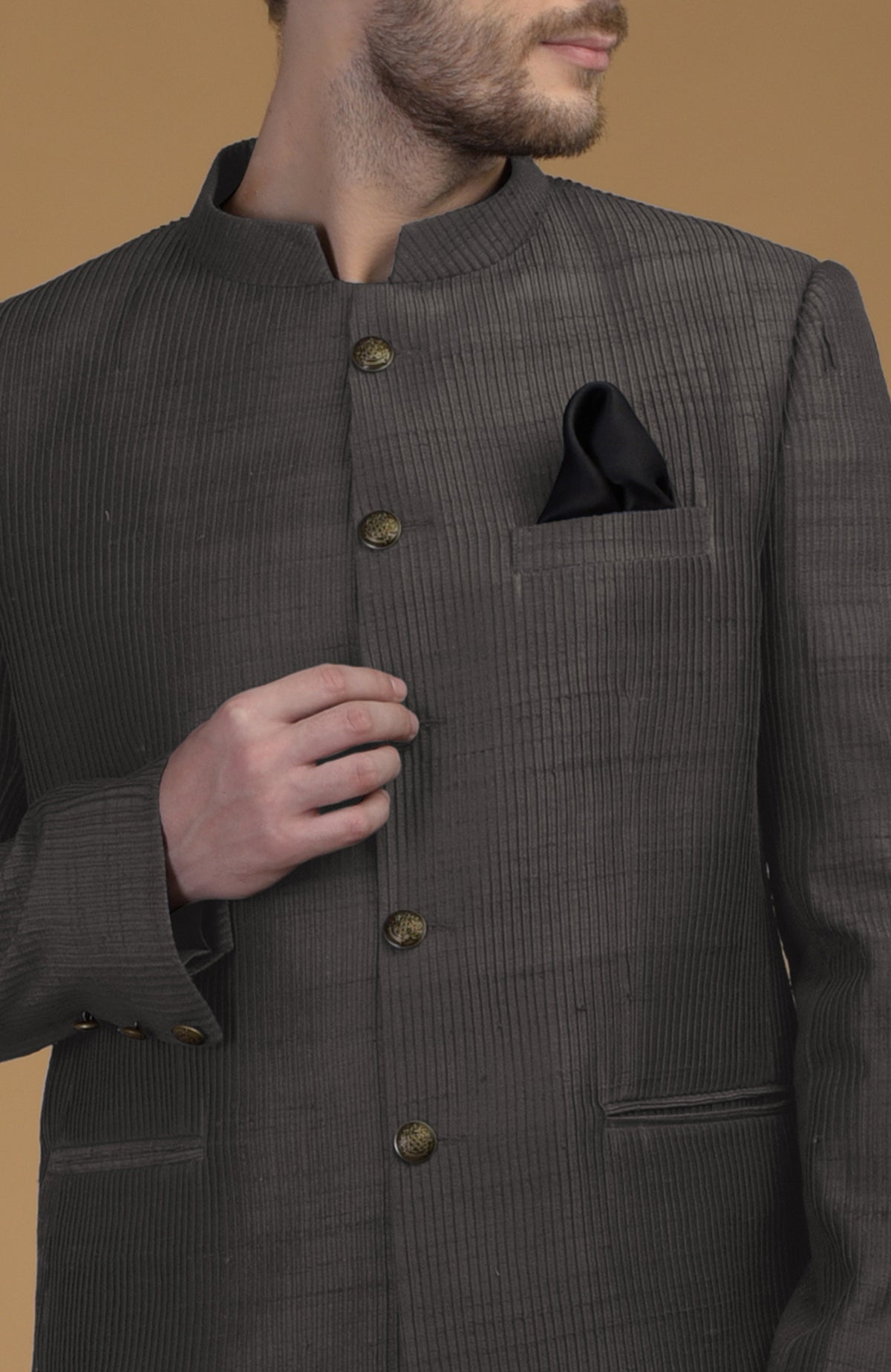 A man models a charcoal grey pintuck pure raw silk bandhgala jacket.