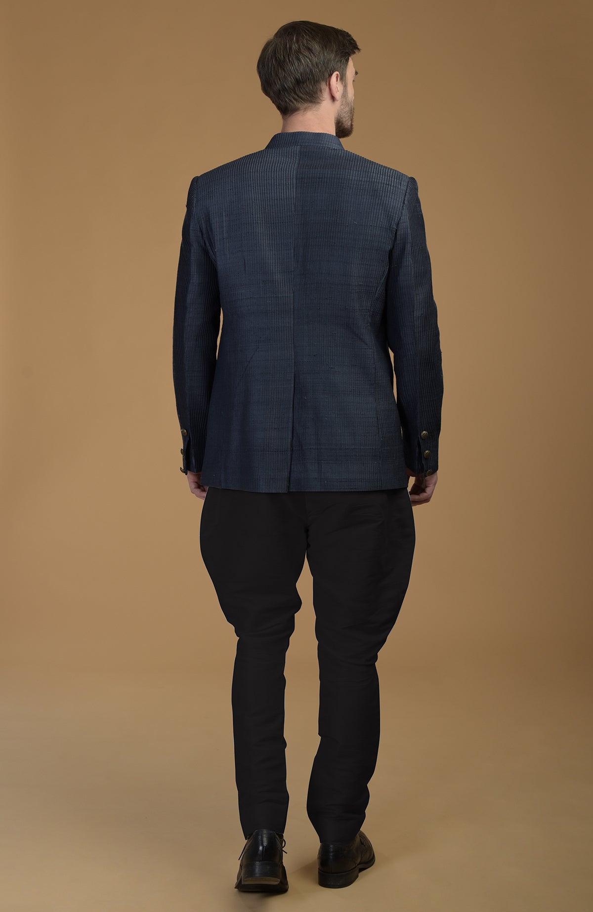 Rear view of a man in an Orion Blue Pintuck Pure Raw Silk Bandhgala Jacket Set.