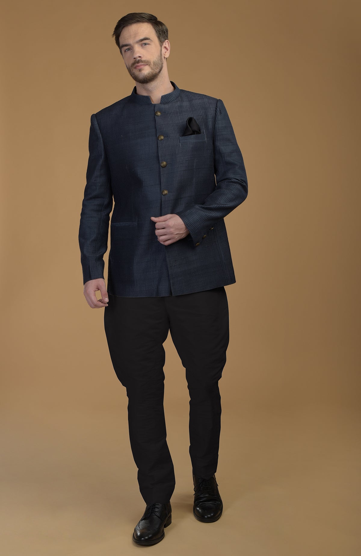 A man models a charcoal grey pintuck pure raw silk bandhgala jacket set.