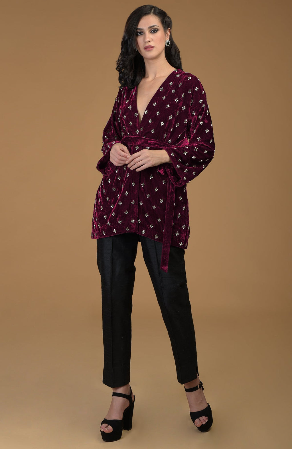 Maroon crystal hand embroidered silk velvet jacket with a waist belt and black pants.