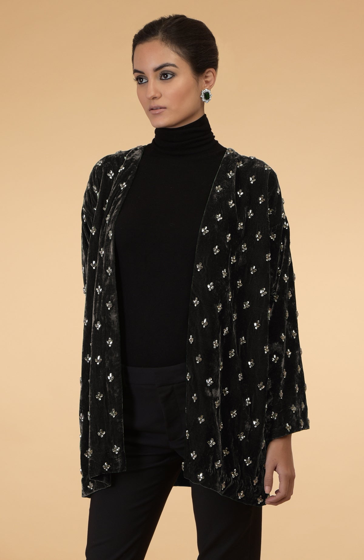 Dark olive silk velvet jacket with crystal hand embroidery, worn over a black turtleneck and pants.