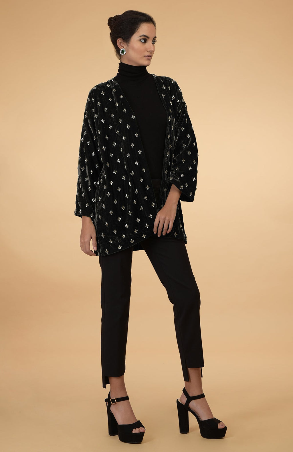 Dark olive silk velvet jacket with crystal hand embroidery, worn over a black turtleneck and pants.