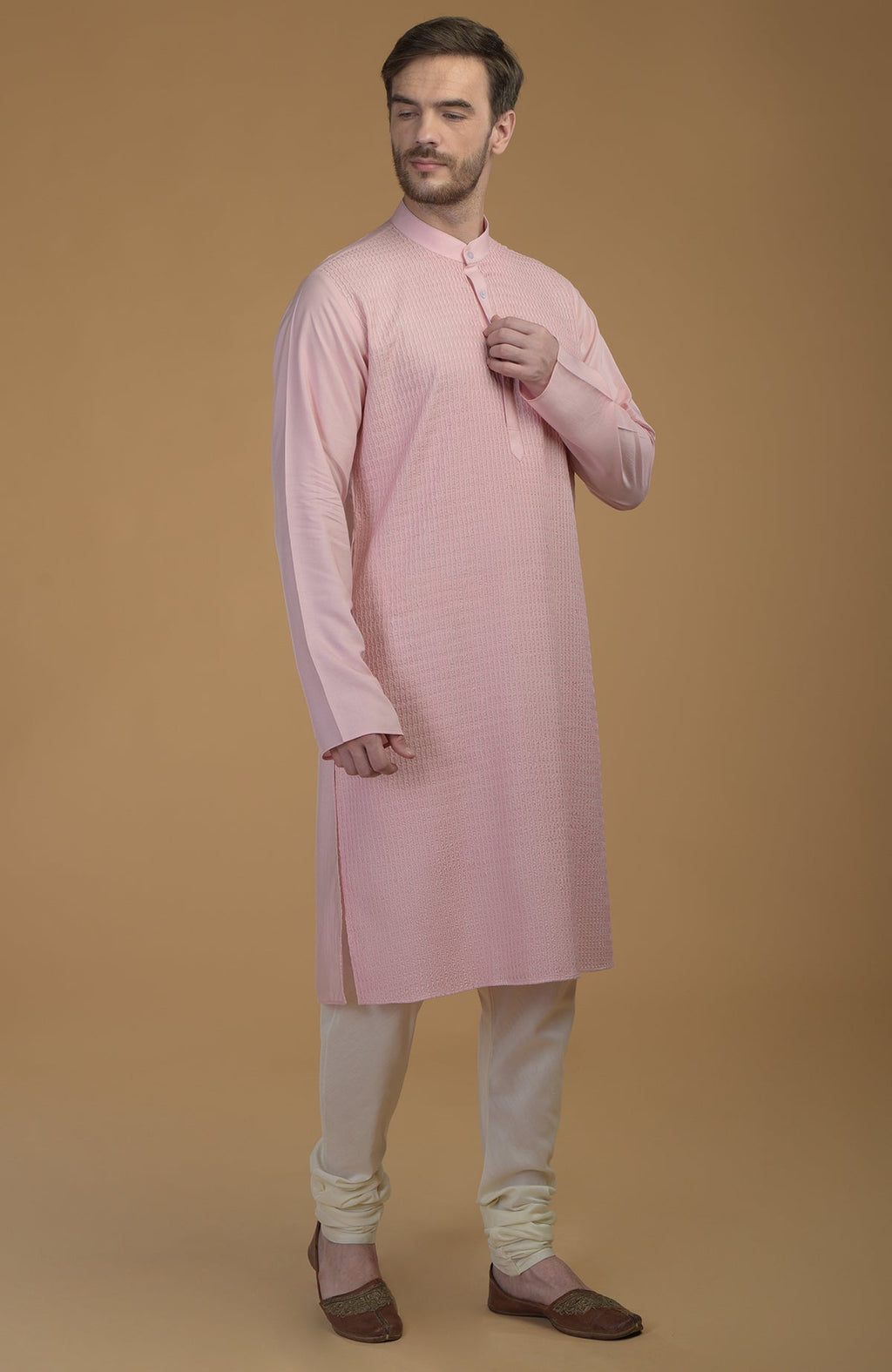 A man models a pale pink kurta with pintuck detail and ivory churidar pants.