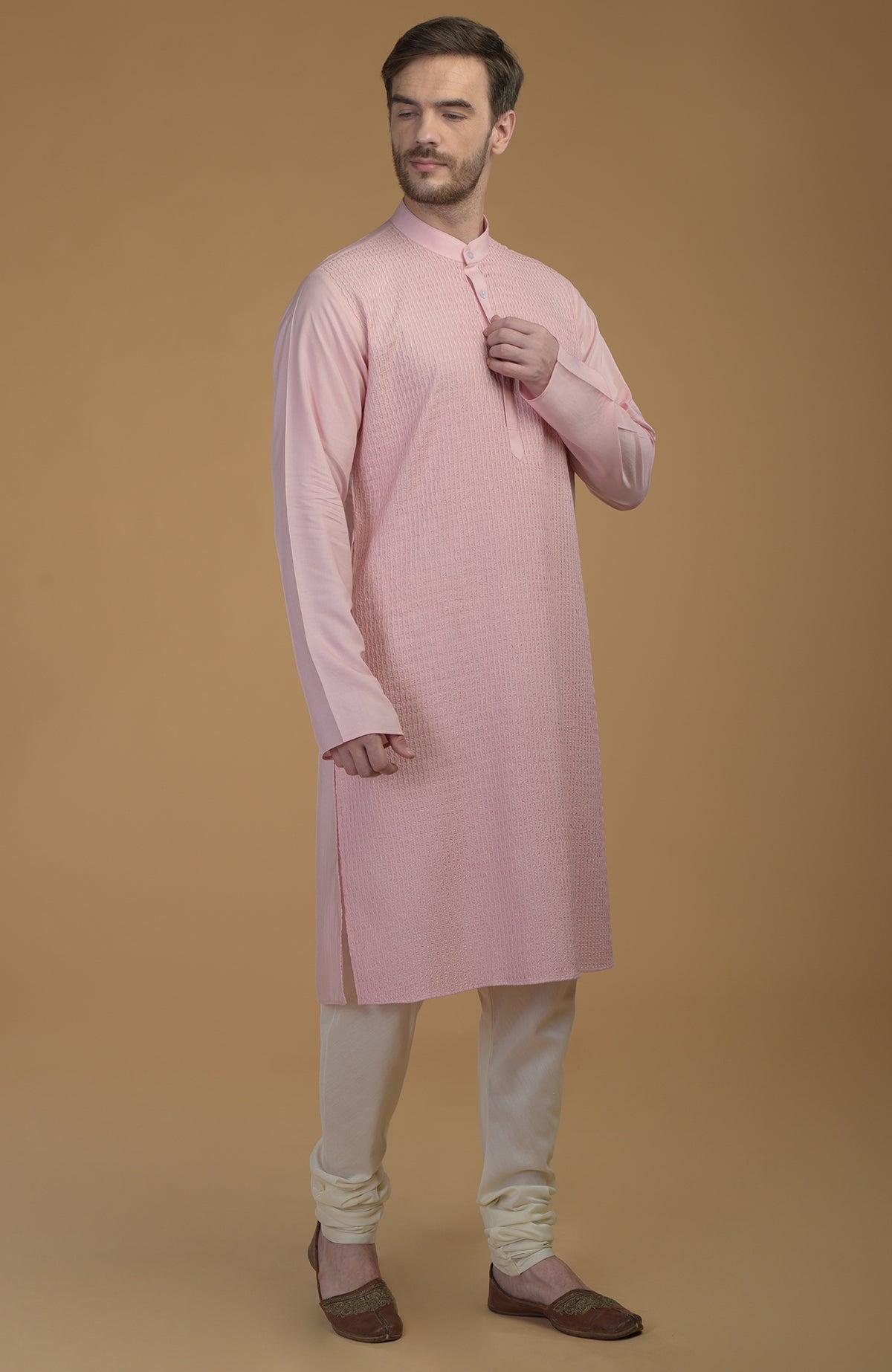 A man models a pale pink kurta with pintuck detail and ivory churidar pants.