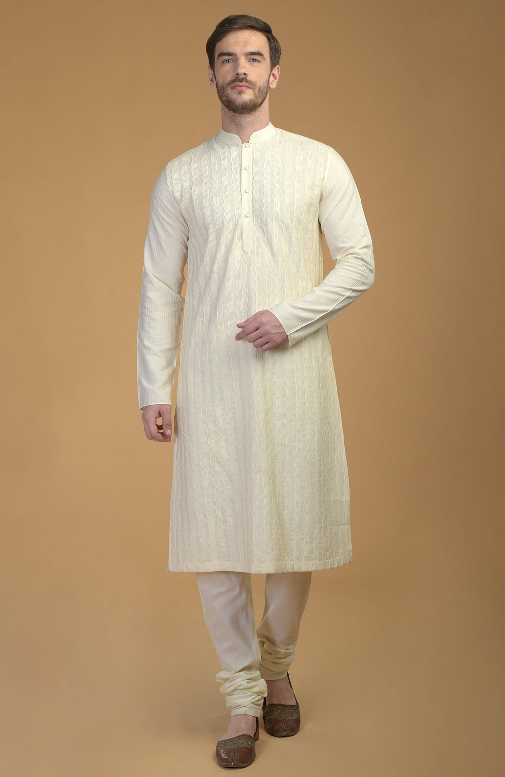 Cream kurta with pintuck and kantha detail, paired with matching churidar and juttis.