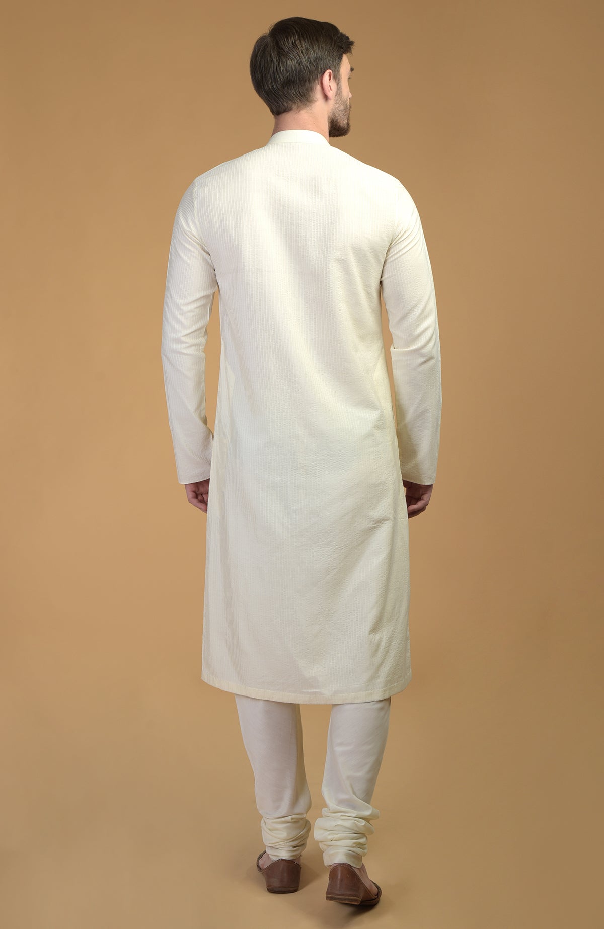 A man from behind wears a cream kurta with pintuck and kantha details and matching pants.