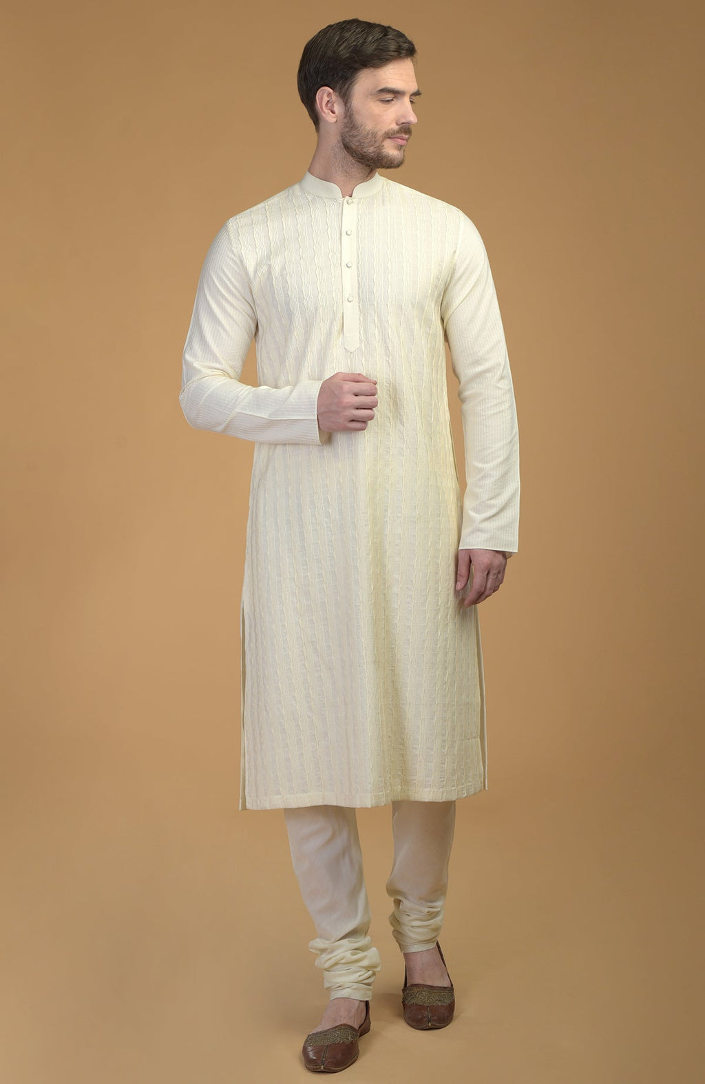 Cream kurta with pintuck and Kantha detail, paired with matching churidar and juttis.
