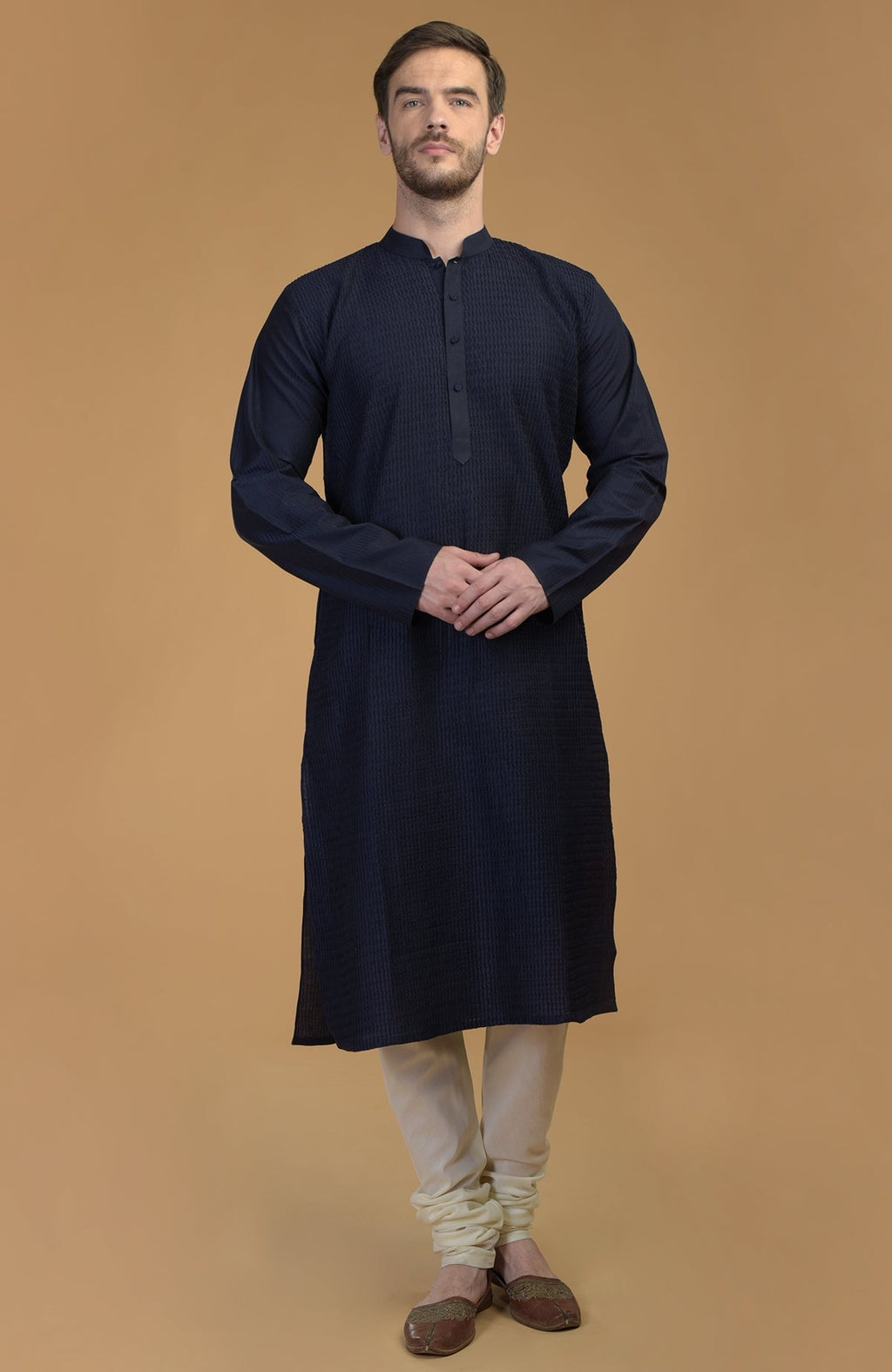 Dark navy kurta with pintuck and kantha detail, paired with ivory churidars and brown juttis.