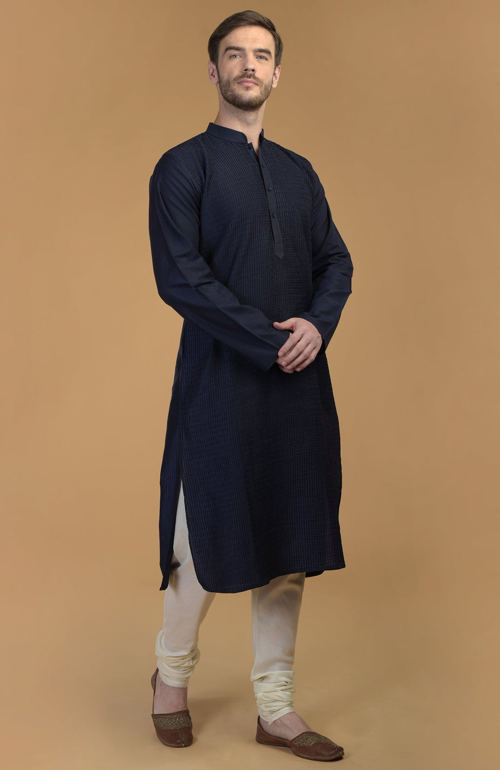 A man models a dark navy kurta with pintuck and kantha details and ivory churidars.