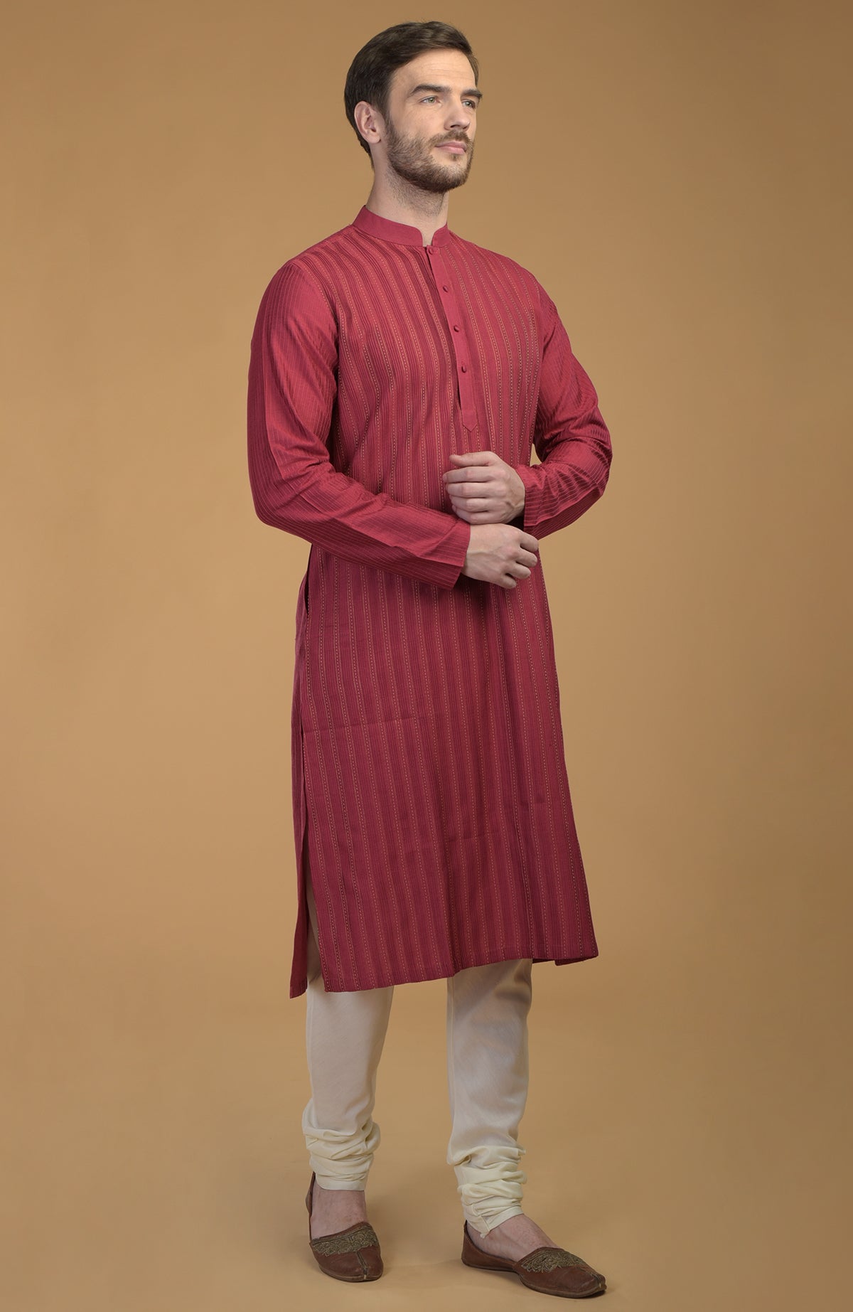A man models a wine-colored kurta with pintuck and kantha details, and ivory churidars.