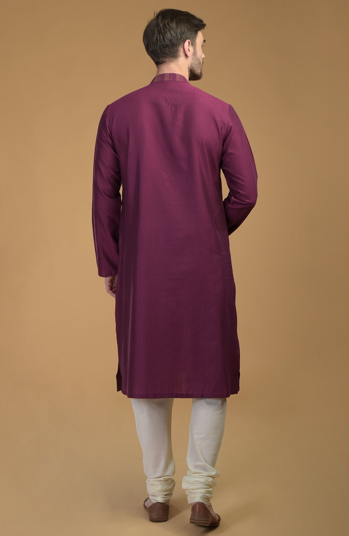 A man from behind wears a plum kurta with pintuck and kantha detail and ivory lowers.