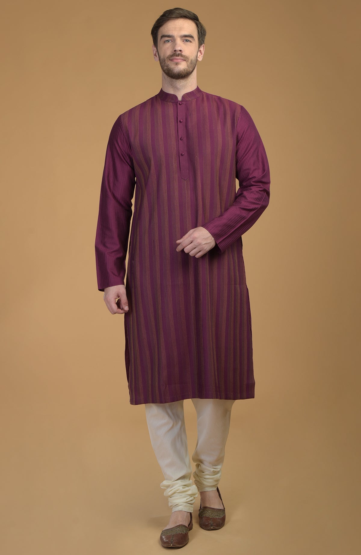 A man stands wearing a plum striped kurta with pintuck and kantha details.