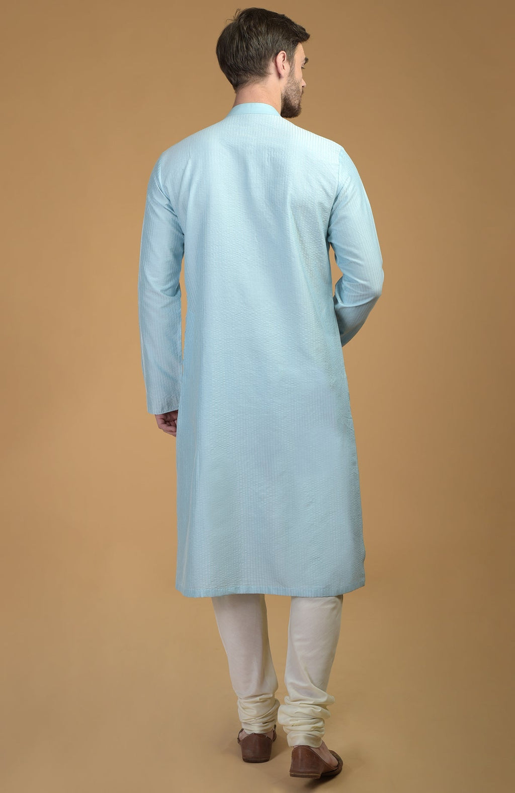 A man from behind wearing an ice blue kurta with pintuck and kantha detail.